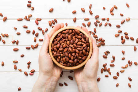 Woman hands holding a wooden bowl with peanuts. Healthy food and snack. Vegetarian snacks of various nuts.の写真素材