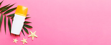 Sunscreen spray bottle. Bottle with sun protection cream and sea shells with tropical green leaf on color background, top view.の写真素材