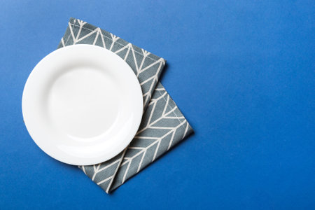 Top view on colored background empty round white plate on tablecloth for food. Empty dish on napkin with space for your design.の写真素材