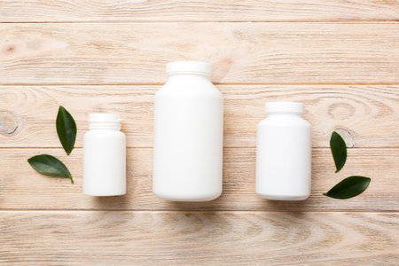 supplement pills with medicine bottle health care and medical top view. vitamin tablets. Top view mockup bottle for pills and vitamins with green leaves, natural organic bio supplement, copy space.の写真素材