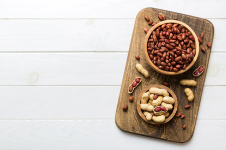 Fresh healthy peanuts in bowl on colored table background. Top view Healthy eating bertholletia...