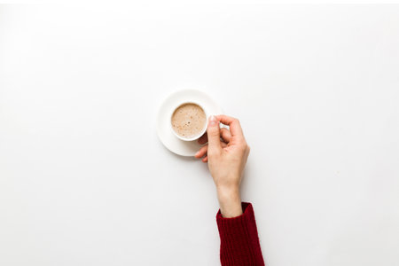 Minimalistic style woman hand holding a cup of coffee on Colored background. Flat lay, top view cappuccino cup. Empty place for text, copy space. coffee addiction. Top view, flat lay.の写真素材