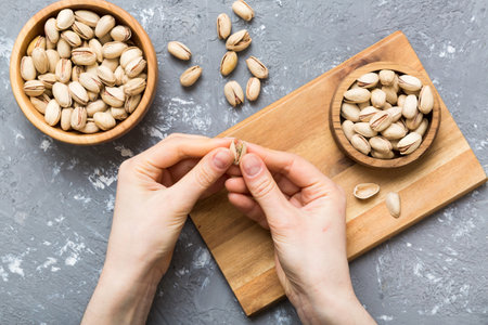 Woman hands holding a wooden bowl with pistachios nuts. Healthy food and snack. Vegetarian snacks of various nuts.の写真素材