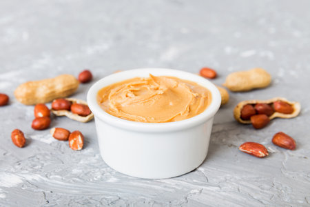 Bowl of peanut butter and peanuts on table background. top view with copyspace. Creamy peanut pasta...
