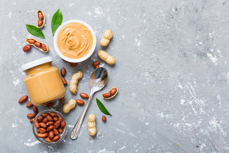 Bowl of peanut butter and peanuts on table background. top view with copyspace. Creamy peanut pasta...