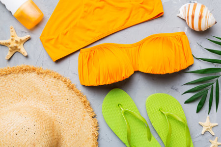 Woman swimwear and beach accessories flat lay top view on colored background Summer travel concept. bikini swimsuit, straw hat and seasheels. Copy space top view.の写真素材