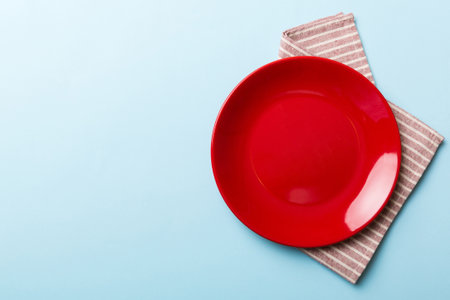 Top view on colored background empty round red plate on tablecloth for food. Empty dish on napkin with space for your design.の写真素材