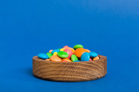 Multicolored candies in a bowl on a colored background. birthday and holiday concept. Top view with copy space.の写真素材
