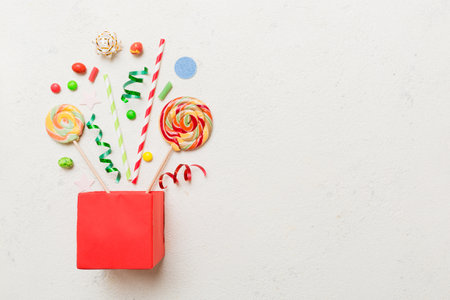 gift box in full corner of assorted traditional candies falling out on colored background with copy space. Happy Holidays sale concept.の写真素材