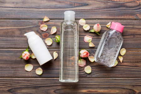 Fancy healthcare bottles for serum, micellar, tonic, toner, lotion, water and cream with rose flower. Natural oranic spa cosmetics concept. Mockup, template, top view.の写真素材