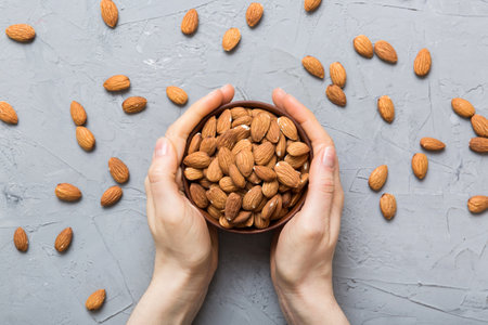 Woman hands holding a wooden bowl with almond nuts. Healthy food and snack. Vegetarian snacks of various nuts.の写真素材