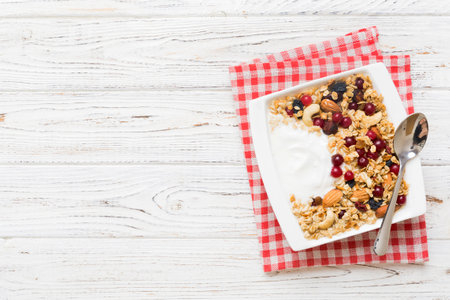 Healthy breakfast food with granola, yogurt, fruits and nuts. Dessert parfait with dried fruits for...