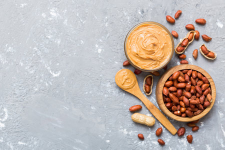 Bowl of peanut butter and peanuts on table background. top view with copyspace. Creamy peanut pasta...