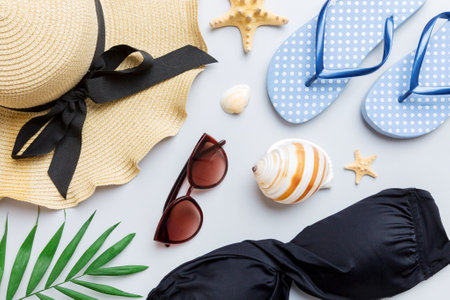 Woman swimwear and beach accessories flat lay top view on colored background Summer travel concept. bikini swimsuit, straw hat and seasheels. Copy space top view.の写真素材