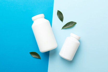 supplement pills with medicine bottle health care and medical top view. vitamin tablets. Top view mockup bottle for pills and vitamins with green leaves, natural organic bio supplement, copy space.の写真素材