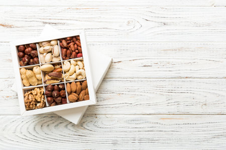 Various varieties of nuts lying in paper box on table background. top view. Health food. Close up, copy space, top view, flat lay. Walnut, pistachios, almonds, hazelnuts and cashews.の写真素材