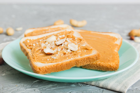 Peanut butter sandwiches or toasts on light table background.Breakfast. Vegetarian food. American...