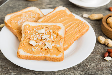 Peanut butter sandwiches or toasts on light table background.Breakfast. Vegetarian food. American...