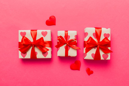 Top view photo of valentine's day decorations gift box with red ribbon bow on colored background....