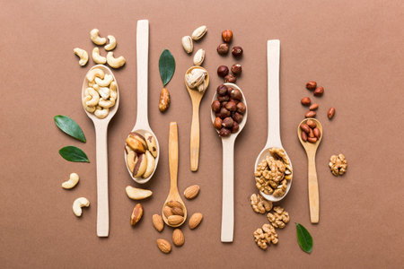 mixed nuts in white wooden spoon. Mix of various nuts on colored background. pistachios, cashews, walnuts, hazelnuts, peanuts and brazil nuts.の写真素材