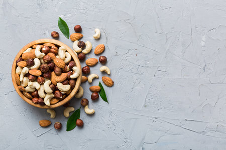 Assortment of nuts in wooden bowl on colored table. Cashew, hazelnuts, walnuts, almonds. Mix of nuts Top view with copy space.の写真素材