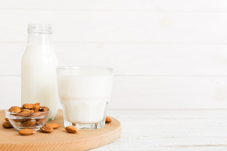 Top view of the almond milk in the glass bottle with almond nuts on the colored table. top view with copy space.の写真素材