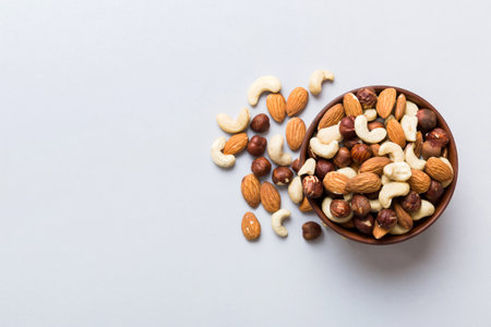 Assortment of nuts in wooden bowl on colored table. Cashew, hazelnuts, walnuts, almonds. Mix of nuts Top view with copy space.の写真素材