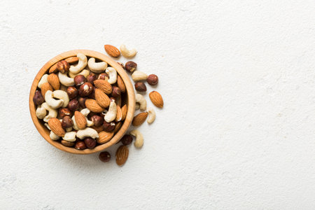 Assortment of nuts in wooden bowl on colored table. Cashew, hazelnuts, walnuts, almonds. Mix of nuts Top view with copy space.の写真素材