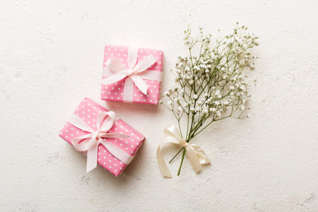 Gift or present box and flower gypsophila on light table top view. greeting card. Flat lay style...