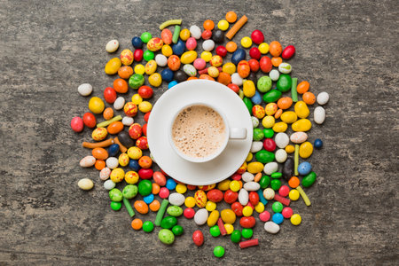 Coffee cup with chocolates and colored candy. Top view on table background with copy space.の写真素材