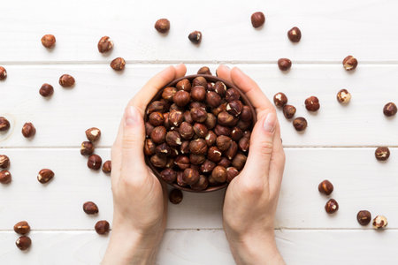 Woman hands holding a wooden bowl with hazelnut nuts. Healthy food and snack. Vegetarian snacks of various nuts.の写真素材