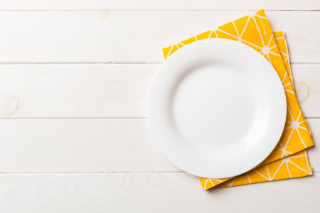 Top view on colored background empty round white plate on tablecloth for food. Empty dish on napkin with space for your design.の写真素材