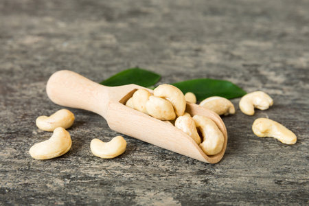 Cashew nuts with green leaves in spoon on table background, Healthy food.の写真素材