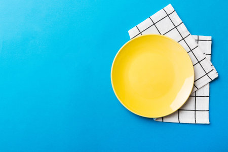 Top view on colored background empty round yellow plate on tablecloth for food. Empty dish on napkin with space for your design.の写真素材