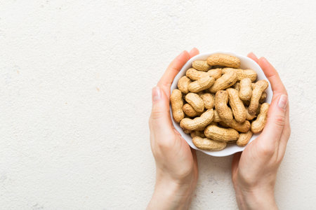 Woman hands holding a wooden bowl with close peanuts. Healthy food and snack. Vegetarian snacks of various nuts.の写真素材