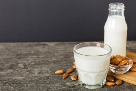 Top view of the almond milk in the glass bottle with almond nuts on the colored table. top view with copy space.の写真素材