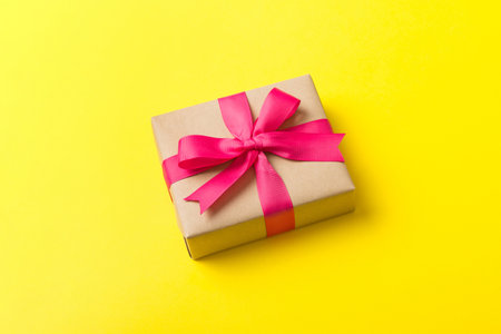 Wrapped christmas or other holiday handmade present in craft paper with colored ribbon. Present box, decoration of gift on table, top view with copy space.の写真素材