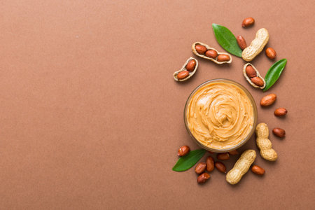 Bowl of peanut butter and peanuts on table background. top view with copyspace. Creamy peanut pasta...
