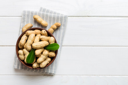 Fresh healthy peanuts in bowl on colored table background. Top view Healthy eating bertholletia...