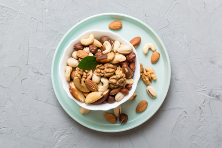 mixed nuts in bowl. Mix of various nuts on colored background. pistachios, cashews, walnuts,...