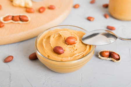 Bowl of peanut butter and peanuts on table background. top view with copyspace. Creamy peanut pasta...