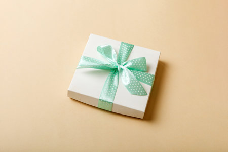 wrapped Christmas or other holiday handmade present in paper with purple ribbon on colored background. Present box, decoration of gift on colored table, top view with copy space.の写真素材