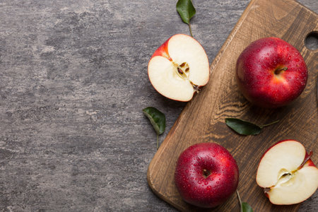 Fresh red apples with green leaves on table. cutting board with knife. top view.