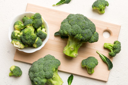 fresh green broccoli on wooden cutting board with knife. Broccoli cabbage leaves. light background. Flat lay.の写真素材