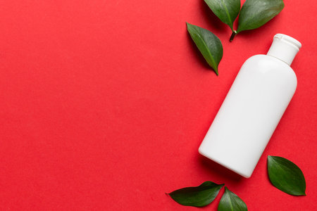 Organic cosmetic product with green leaves on color background. Copy space, flat lay.の写真素材