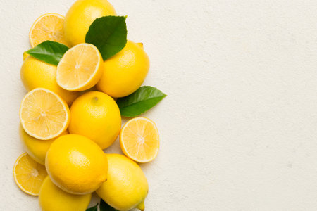 Many fresh ripe lemons with green leaves on colored background, top view, space for text.の写真素材