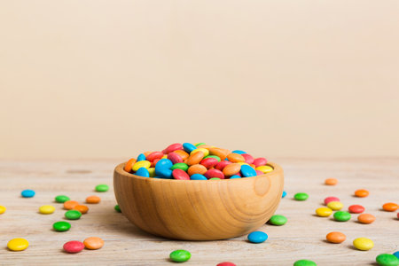 Multicolored candies in a bowl on a colored background. birthday and holiday concept. Top view with copy space.の写真素材