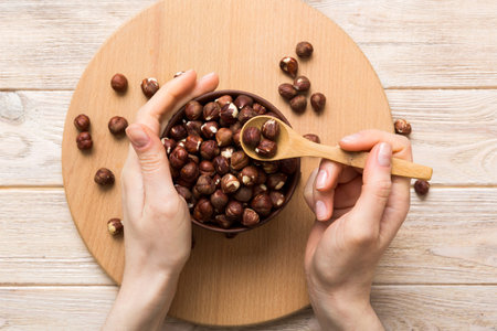 Woman hands holding a wooden bowl with hazelnut nuts. Healthy food and snack. Vegetarian snacks of various nuts.の写真素材