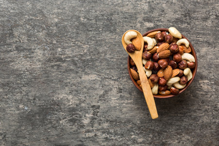 Assortment of nuts in wooden bowl on colored table. Cashew, hazelnuts, walnuts, almonds. Mix of nuts Top view with copy space.の写真素材