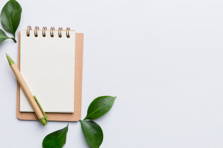 eco-friendly Empty notebook with pen and green leaf on Colored background for note.の写真素材